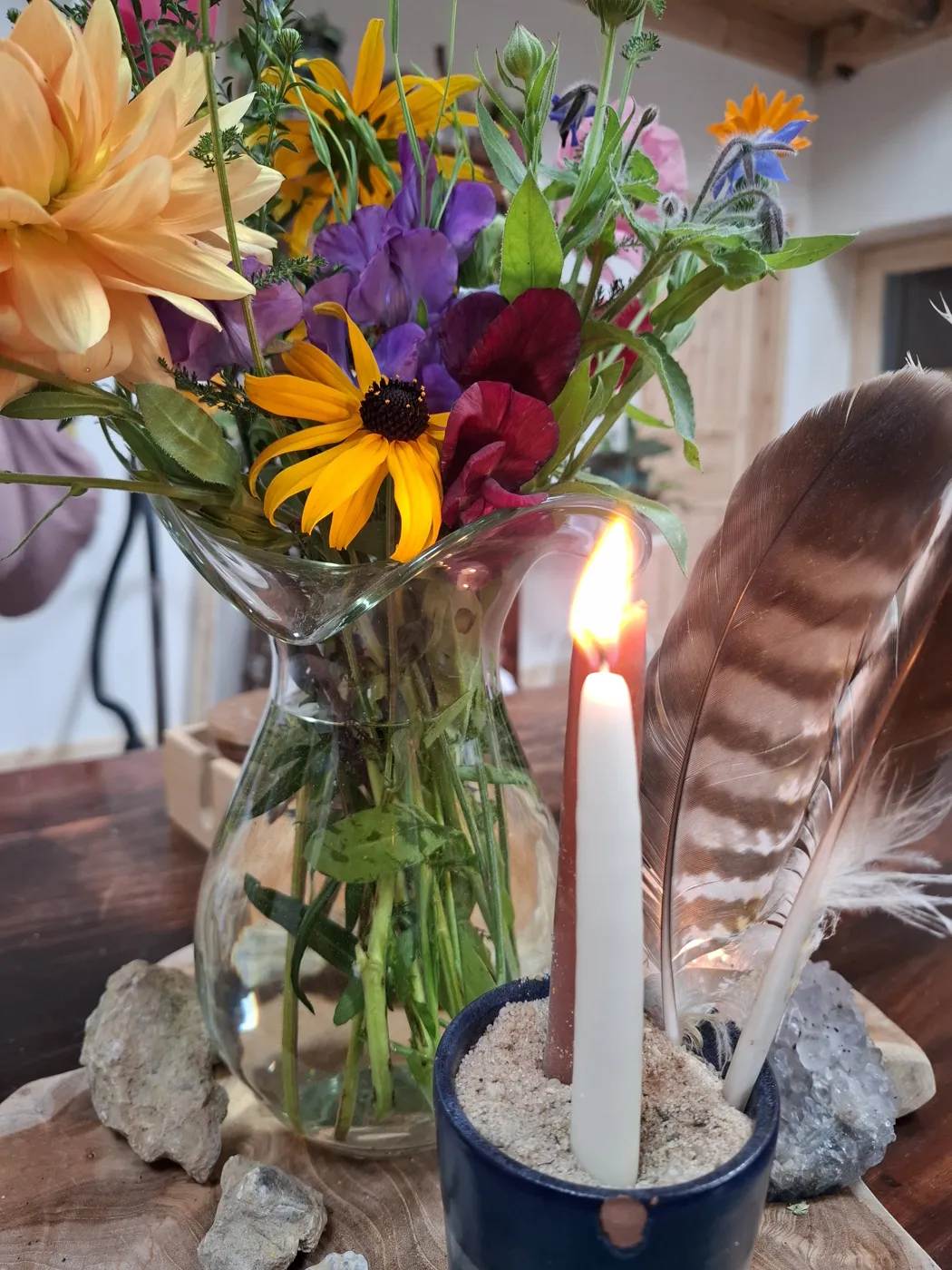 Jahreszeitentisch im Sommer mit Blumen, Kerze und Feder
